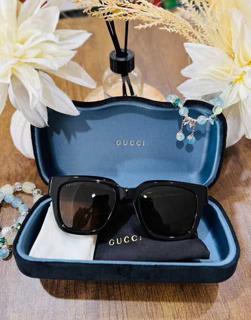 MAY Kaya Gucci black rectangular sunglasses in blue case, angled view